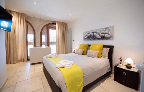 a bedroom with a large bed with yellow pillows at Villa Tesoro in Cisternino