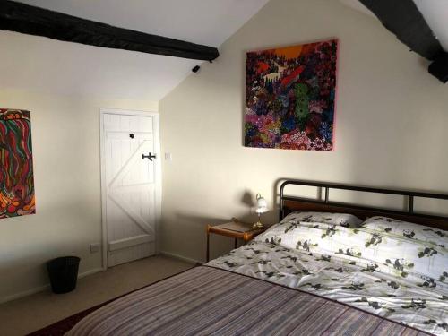 a bedroom with a bed and a painting on the wall at Lavender Cottage, 3 School Road, Clun, Shropshire in Clun