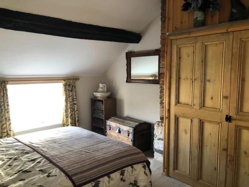a bedroom with a bed and a dresser and a window at Lavender Cottage, 3 School Road, Clun, Shropshire in Clun