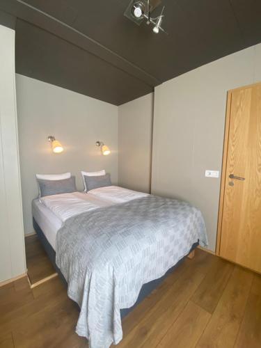 a bedroom with a large bed with a white blanket at North West Restaurant & Guesthouse in Víðigerði