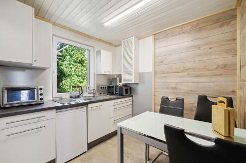 a kitchen with white cabinets and a table at Ferienhaus Zeulenrodaer Meer in Stelzendorf