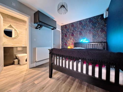 1 dormitorio con cuna negra y pared azul en Boutique Annexe Close To Central Norwich & Airport, en Norwich