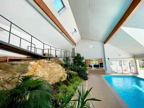 une maison avec une piscine et un mur de roche dans l'établissement Villa avec piscine d'intérieur “ Losalia “, à Talant