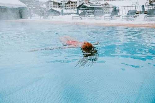 a person swimming in a pool in the water at kerii - adults boutique hotel in Saalbach Hinterglemm