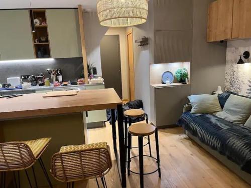 une cuisine et un salon avec une table et des tabourets dans l'établissement Appart Centre Chamonix Grande Terrasse Mont Blanc, à Chamonix-Mont-Blanc