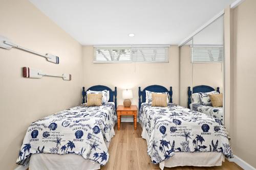 紐波特海灘的住宿－Three Bedroom Three Bath Home w Patio 1 block from beach，卧室内的两张床,配有蓝色和白色的床上用品