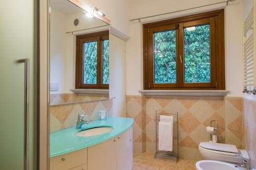 La salle de bains est pourvue d'un lavabo, de toilettes et de fenêtres. dans l'établissement Beautiful villa with stunning lake view, à Torri del Benaco