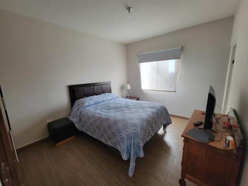a bedroom with a bed and a desk with a television at Departamento EMPRESARIAL cerca de zona industrial in Chihuahua