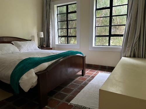 a bedroom with a large bed and two windows at The Zambarao Farm House in Naivasha