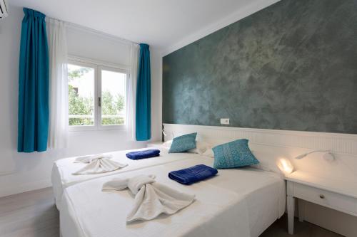 Schlafzimmer mit einem Bett mit blauen Vorhängen und einem Fenster in der Unterkunft FERRERA SUITES in Cala Ferrera