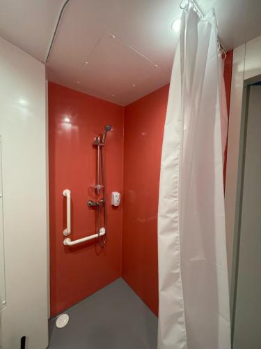 y baño con ducha y pared roja. en Smart Appart Le Havre 97, en Le Havre