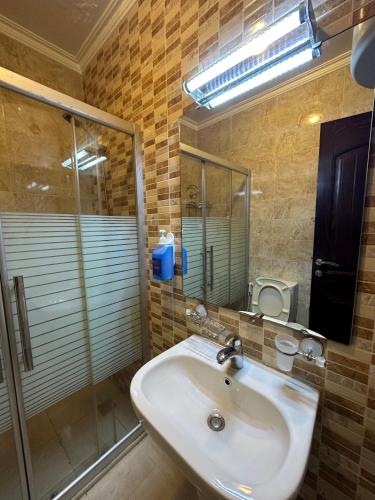 y baño con lavabo y ducha acristalada. en al-burj apart 7th circle en Amán