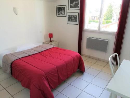 1 dormitorio con cama roja y ventana en Chambre avec salle de bain privative comme à l'hôtel et "salon-cuisine" à partager avec les 4 autres locataires, en Saint-Maurice-de-Gourdans
