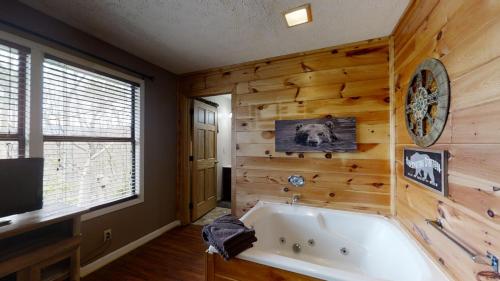 a bath tub in a room with a wooden wall at Heaven's Door in Pigeon Forge