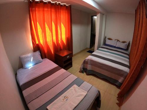 - une petite chambre avec 2 lits et une fenêtre dans l'établissement Millpu Hostal, à Ayacucho