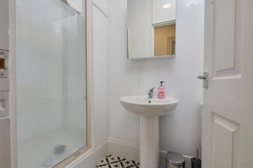 a white bathroom with a sink and a shower at Large 4 bedroom flat, 5 mins to St James', parking in Elswick