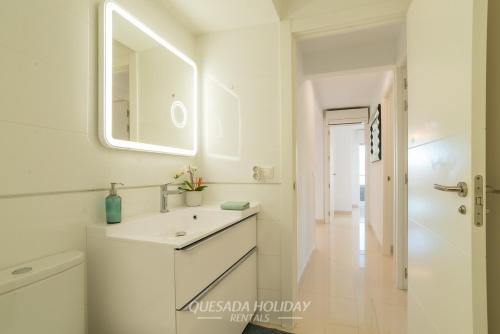 a white bathroom with a sink and a mirror at La Perla Benidorm Apartment seaview & pool Levante Beach in Benidorm