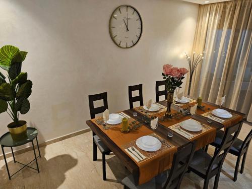 a dining room table with chairs and a clock on the wall at Genius 3 Bedroom Apartment with Beautiful Terrace Space, Casablanca in Casablanca