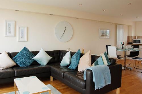 a living room with a couch and a clock on the wall at Sunset Bay Beach House in Tywyn in Tywyn