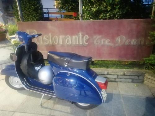 a blue scooter parked in front of a sign at Hotel Tre Denti in Cantalupa
