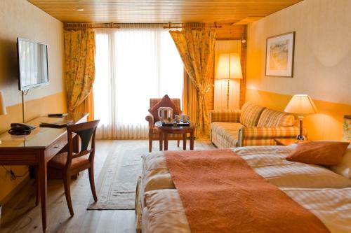ヴェンゲンにあるHotel Silberhorn - Residences & Spa Wengenのベッドとデスクが備わるホテルルームです。