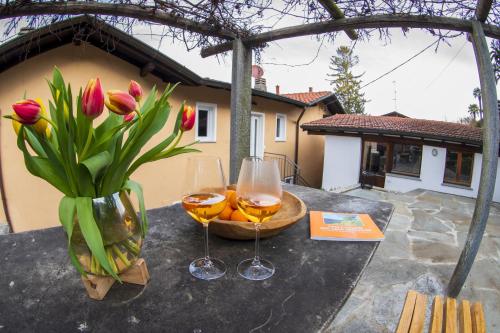 zwei Gläser Wein und eine Vase Blumen auf dem Tisch in der Unterkunft Casa Calma in Pino Lago Maggiore