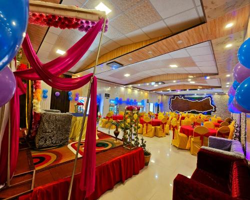 un salón de banquetes con mesas rojas y amarillas y globos en Afno Ghar Temple Resort en Dhantardhi