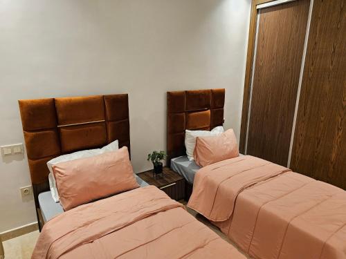 two beds in a room with orange sheets at 3 Bedroom Luxury Apartment with Premium Amenities for Larger Families in Casablanca