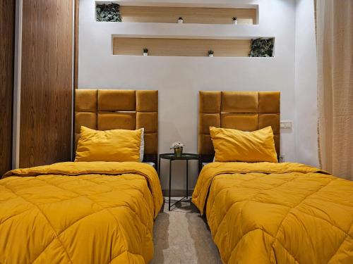 two beds in a room with yellow blankets and pillows at 3 Bedroom Luxury Apartment with Premium Amenities for Larger Families in Casablanca
