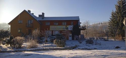 una casa con nieve en el suelo delante de ella en Agroturystyka U Baltazara en Duszniki Zdrój
