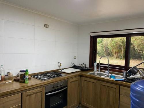 a kitchen with a stove and a sink and a window at Casa campo en plena naturaleza 3 dormitorios y 2 baños in Lago Ranco