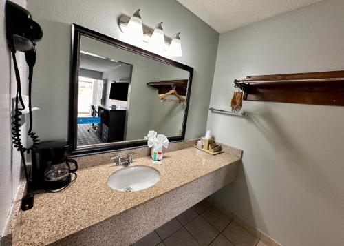 uma casa de banho com um lavatório e um espelho grande em Red Carpet Inn - Natchez em Natchez