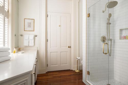 a white bathroom with a shower and a sink at The Jasmine House in Charleston