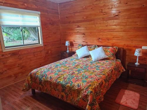 Un dormitorio con una cama con paredes de madera y una ventana en Cabañas los tres hermanos, en Linares