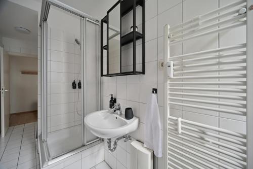 a white bathroom with a sink and a shower at Goodliving Apartments mit Netflix Büro und Parkplatz in Essen
