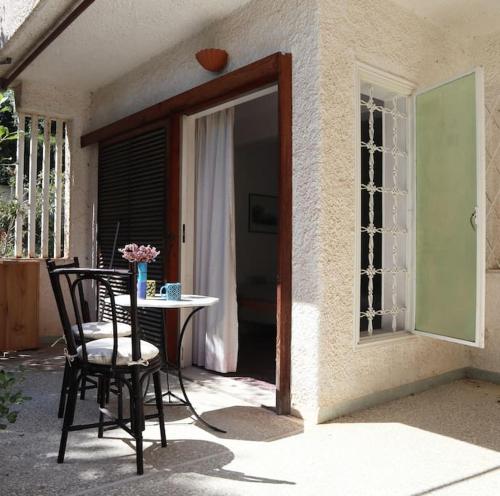 a patio with a table and chairs and a window at Sunny summer house with sea view in Koropíon