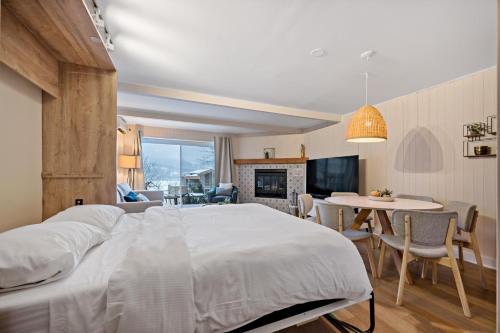a bedroom with a large bed and a dining room at Hotel du lac by Rendez-Vous Mont-Tremblant in Mont-Tremblant