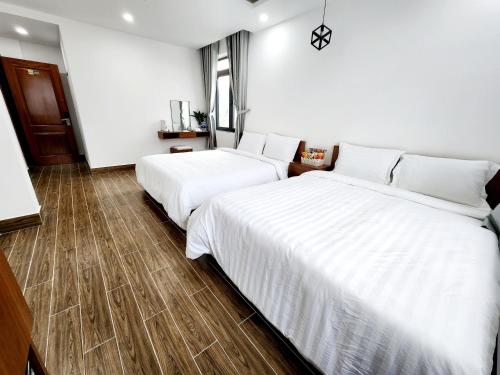 two beds in a hotel room with white sheets at Happy Bun Hotel Da Lat in Da Lat
