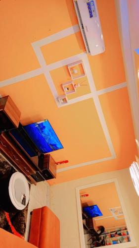 ein Wohnzimmer mit orangefarbenen Wänden und einem Flachbild-TV in der Unterkunft Seïf Industry in Ouagadougou
