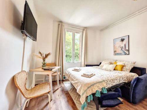 a bedroom with a bed and a table and a tv at L'évasion Marine à la plage 2P in Houlgate