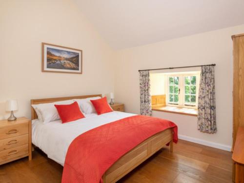 a bedroom with a bed with red pillows and a window at 3 Bed in Askham 93429 in Askham