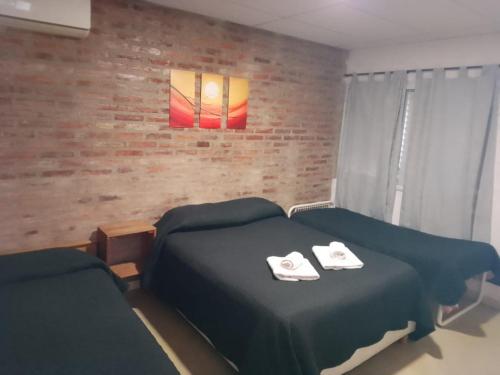 a bedroom with two beds and a brick wall at LOS Teros dptos 3 5 3 4 0 9 2 8 1 5 in Villa María
