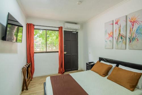 a bedroom with a bed with orange curtains and a window at Jaco Lodge Quiet Place in Jacó