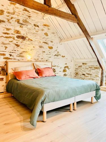 un lit dans une chambre avec un mur en pierre dans l'établissement Le Cinquante, à Groix