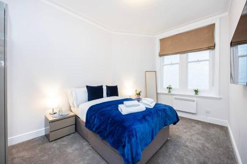 a bedroom with a large bed with blue sheets and a window at Stylish Studio in Leicester Square in London