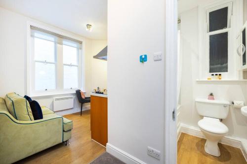 a bathroom with a couch and a toilet and a window at Stylish Studio in Leicester Square in London