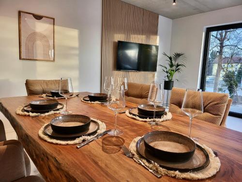 a wooden table with plates and wine glasses on it at SiOUX: stilvolles Designapartment am Bodensee in Lindau-Bodolz