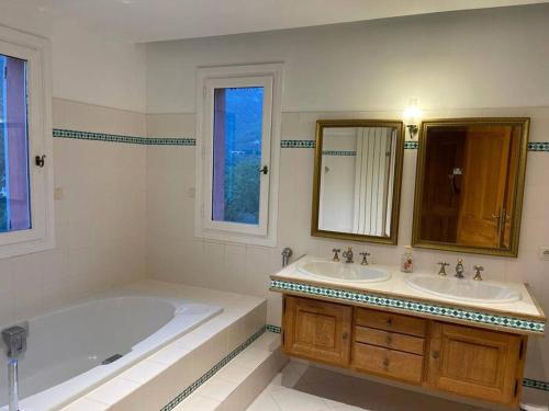 uma casa de banho com 2 lavatórios, uma banheira e um espelho. em Grande villa de 8 chambres avec piscine et tennis em Tourrettes-sur-Loup