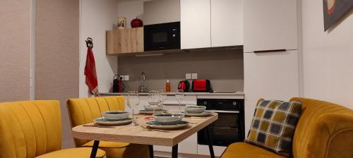 a dining room table with yellow chairs and a kitchen at Aux Sons des Cloches - Chalet avec Jacuzzi, Sauna et vue panoramique in Rosteig
