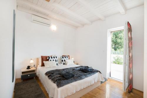 a white bedroom with a bed and a window at Moenia Apartments in Milna